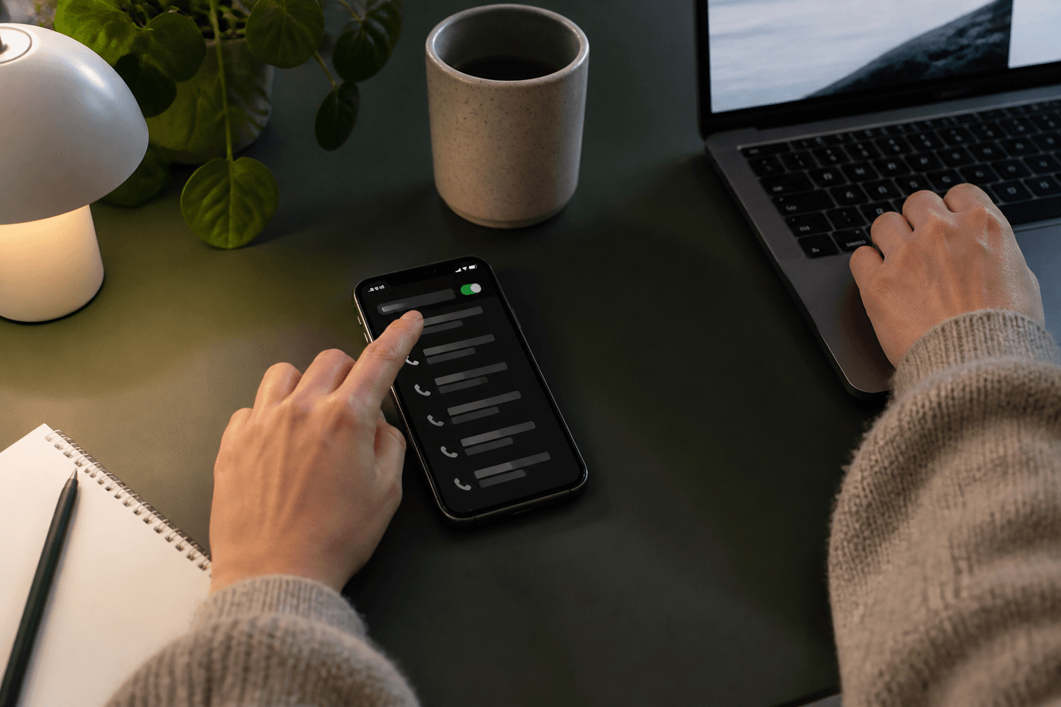 Person der gennemgår gentagne opkald på sin telefon ved et roligt skrivebord